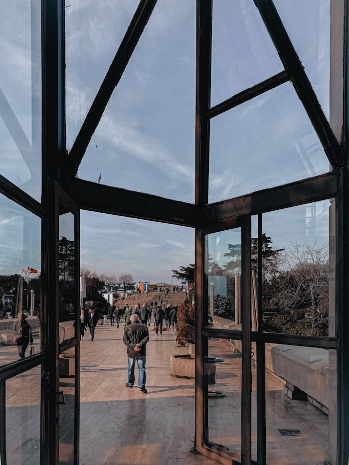 Services View through glass walls onto a busy urban promenade with people walking.