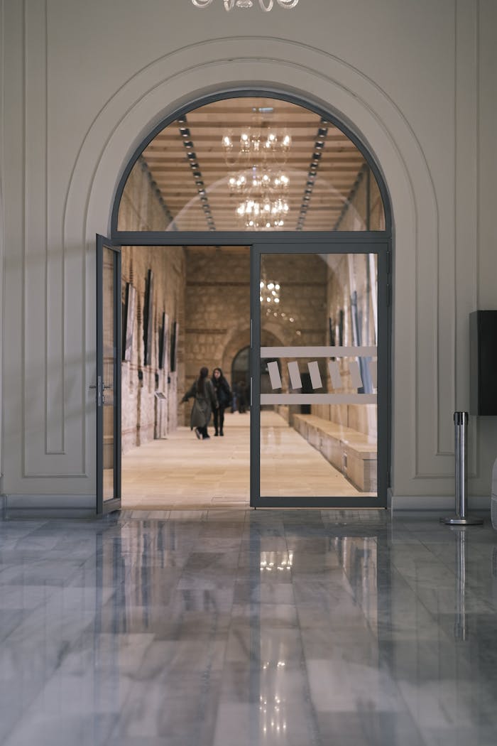 Mastering the First Impression: Your intriguing post title goes here Elegant interior view of a corridor with an open glass door and people walking inside.